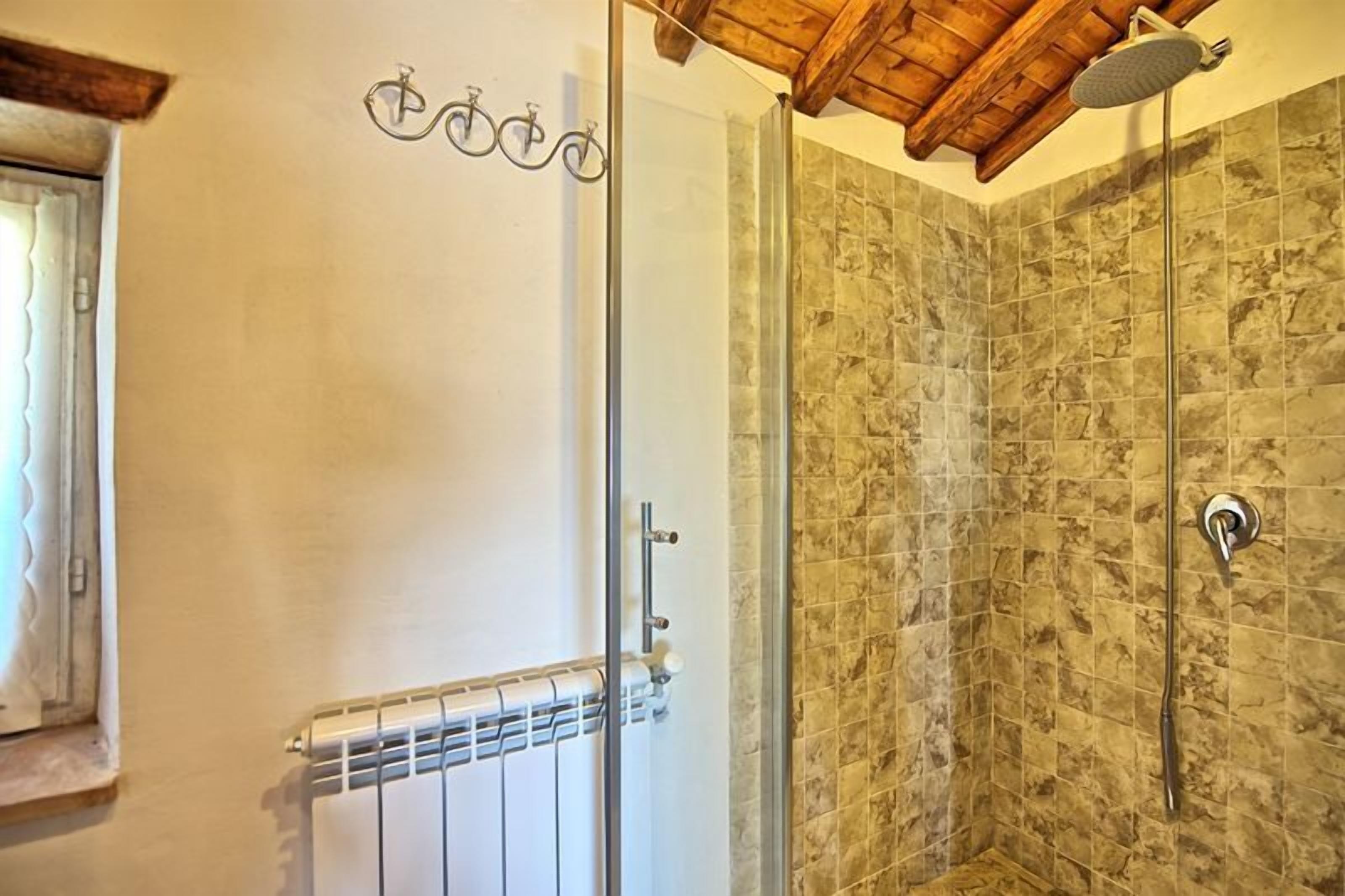 Une douche avec une porte en verre, un plafond en bois et un mur carrelé.