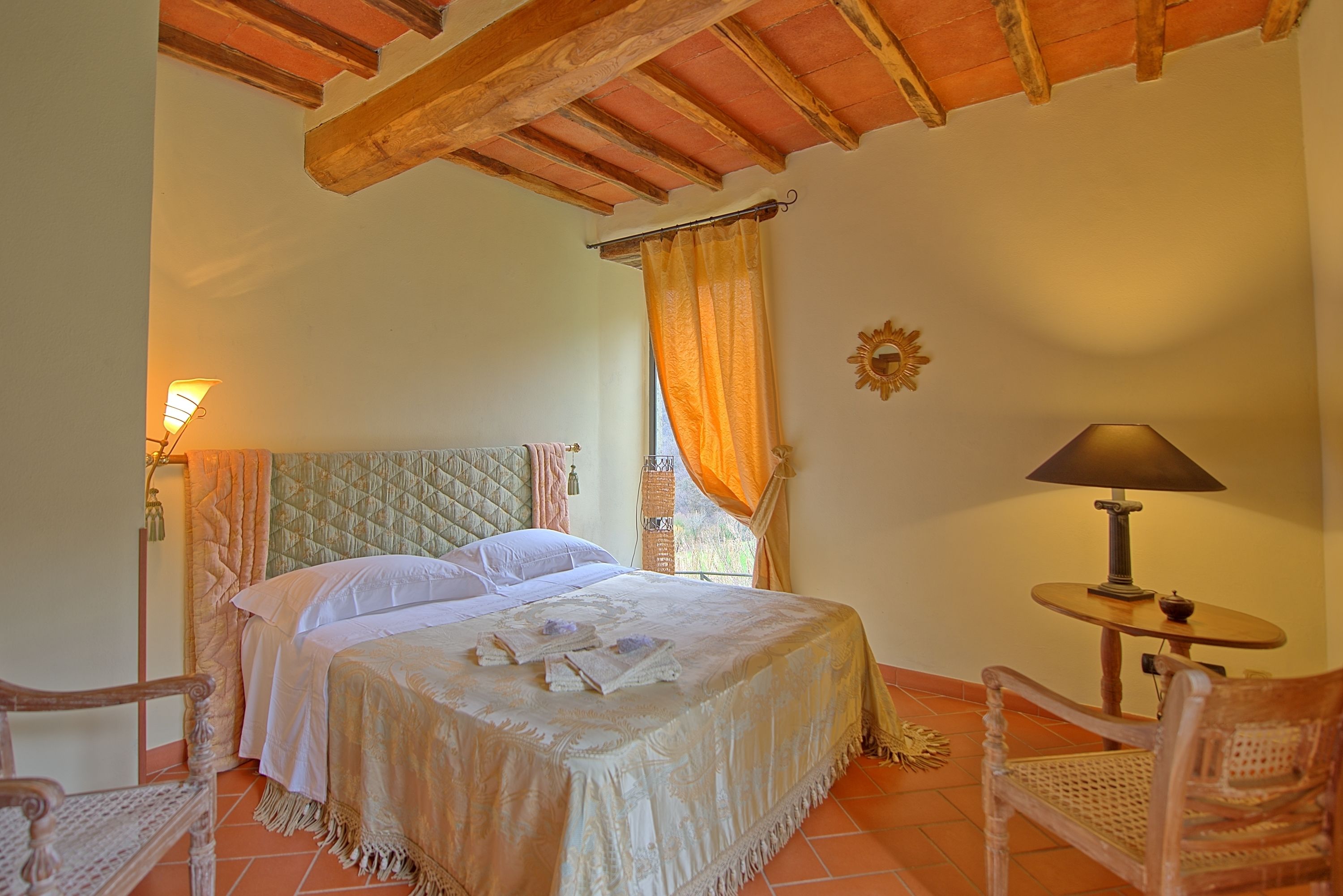 A bedroom with a bed, a nightstand, a chair, and a lamp.
