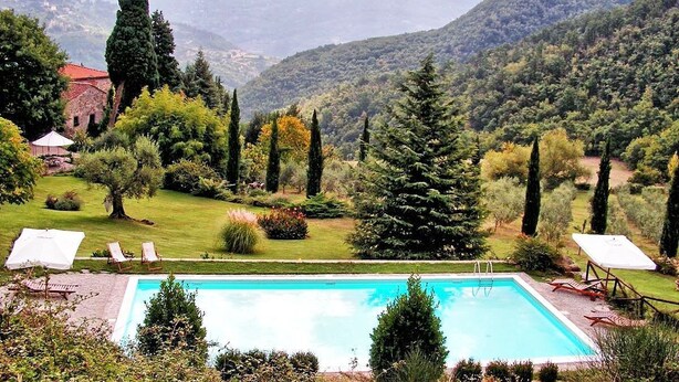 A rectangular pool with a clear blue water surface, surrounded by a well-maintained lawn and various trees. - Casa Uscioli (Pontassieve)