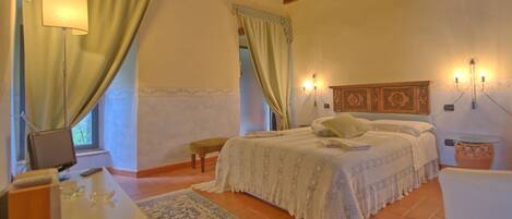 A bedroom with a bed, bedside table, lamp, and a window with curtains.