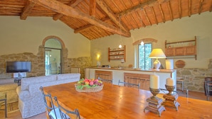 A rustic dining area with a wooden table, stone walls, and a stone fireplace. - Casa Uscioli (Pontassieve)