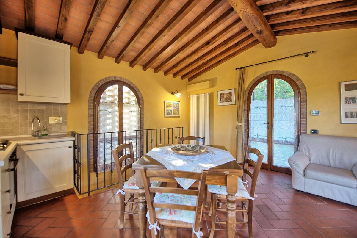 A cozy dining area with a wooden table and chairs, a kitchen with a sink and cabinets, and a balcony with a view.