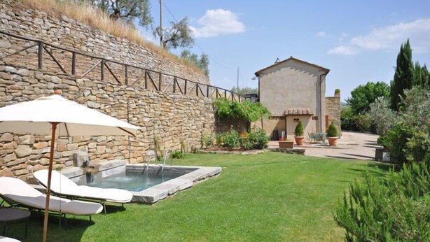 A stone wall, a small pool, lounge chairs, and a building with a sloped roof. - Villa Calcinaio (Cortona)