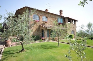 A stone house with a sloped roof, arched windows, and a small balcony.
