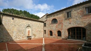 Un patio con muros de piedra, una estatua y un suelo de ladrillo.