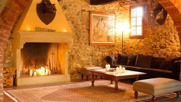 Una habitación acogedora con chimenea de piedra, un sofá y una mesa con velas.