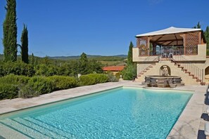 A swimming pool with a covered outdoor area, a staircase leading to a terrace, and a statue in the center. - Villa Guia (Bucine)