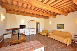 A spacious living area with a wooden ceiling, a dining table, a sofa, and a television. - Talamone (Orbetello)