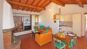 Una sala de estar acogedora con chimenea, un sofá y un comedor con una mesa preparada para dos.