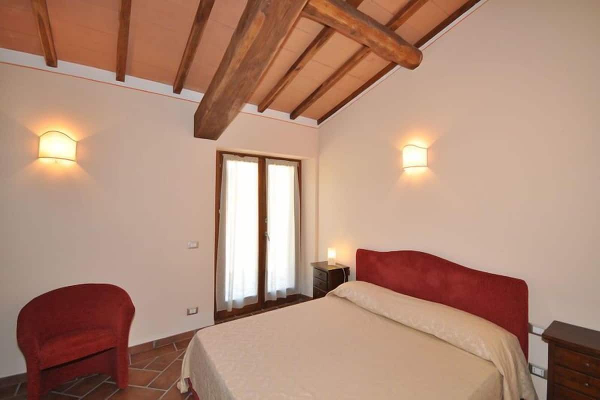 Una camera da letto con un letto, una sedia e due luci a parete.