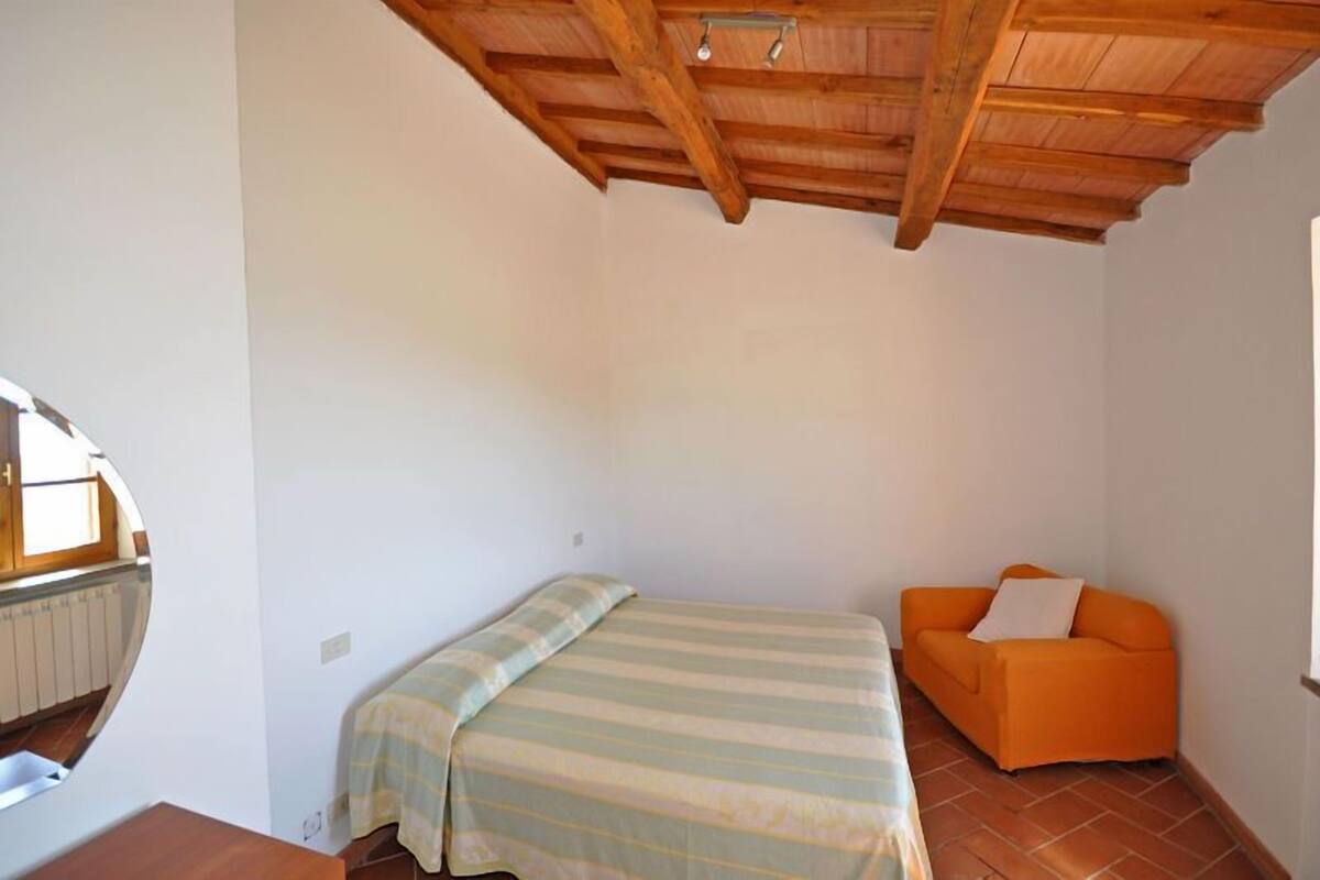 Un piccolo alloggio in un'unica stanza, con un letto, un divano e un soffitto in legno.
