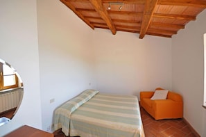 A small, single-room accommodation with a bed, a sofa, and a wooden ceiling. - Talamone (Orbetello)
