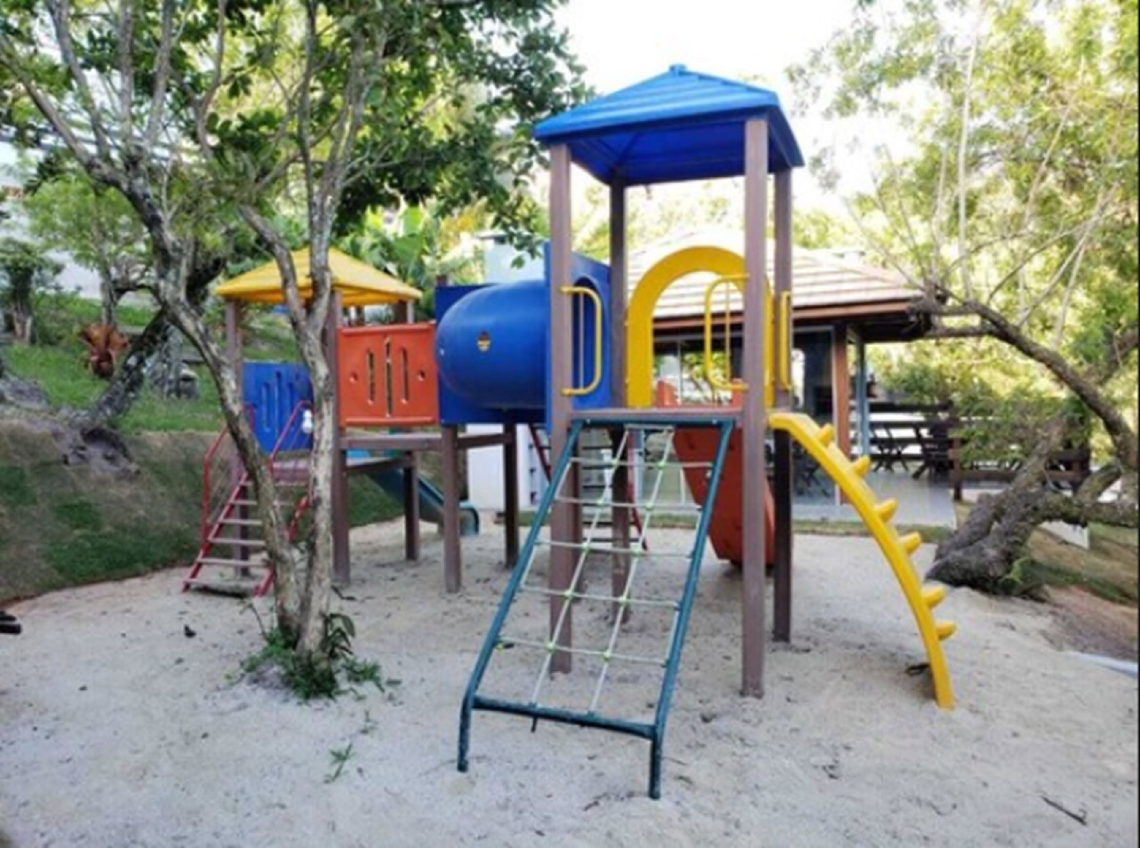 Une aire de jeux avec une structure d’escalade, des toboggans et un espace de jeux abrité.