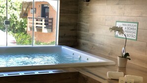 Un baño moderno con una bañera grande, suelo de madera, una pequeña planta en maceta y un cartel en la pared.