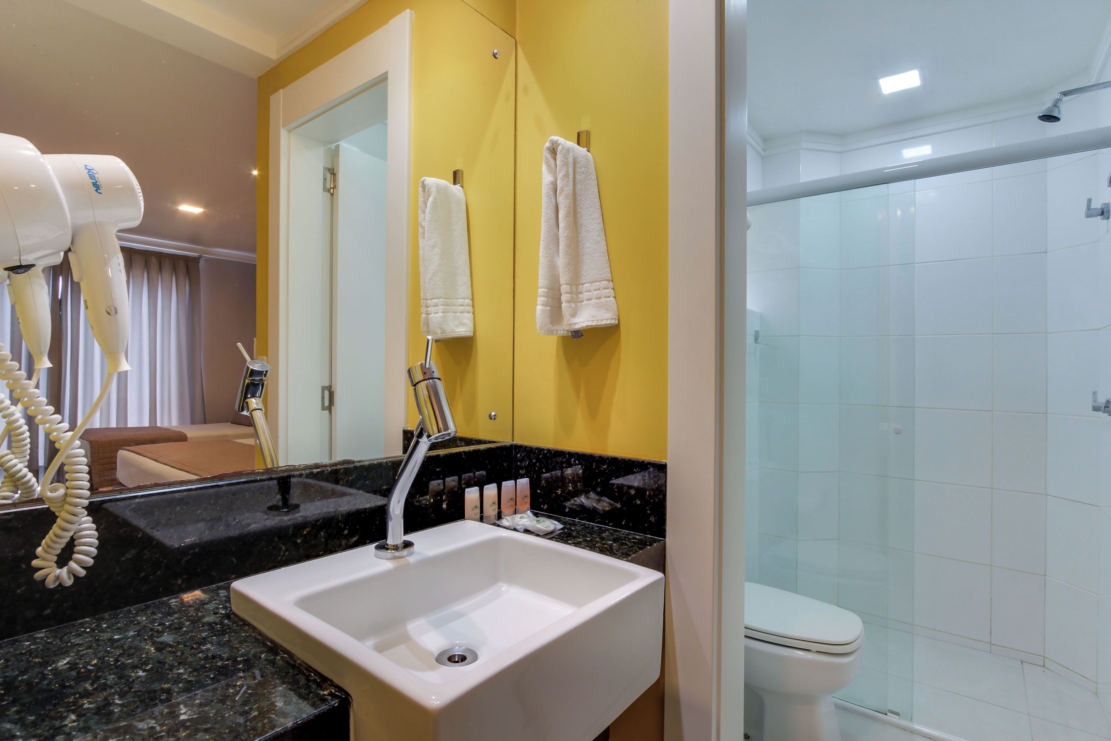 A bathroom with a sink, mirror, and a glass-enclosed shower.