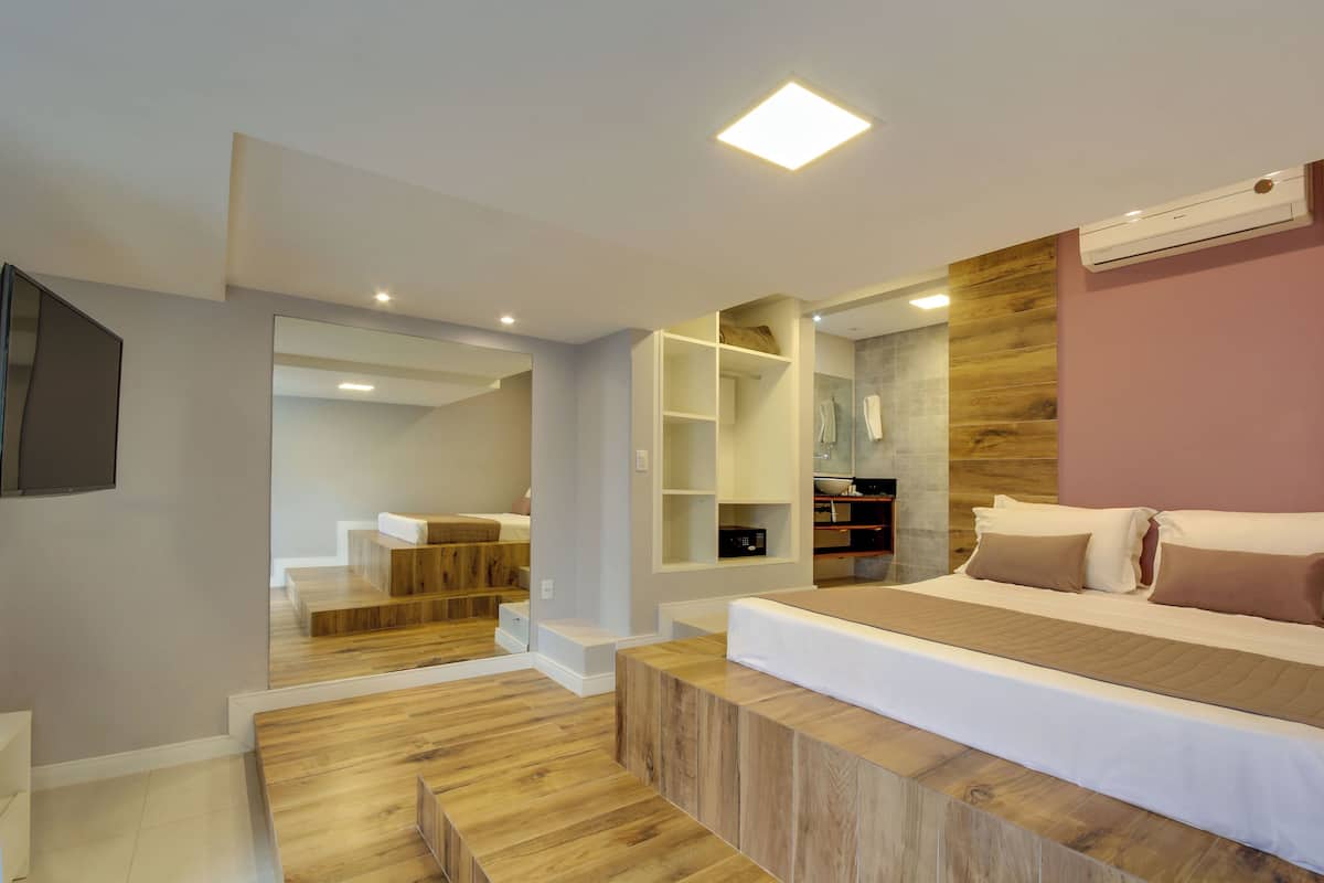 A modern bedroom with a large bed, built-in shelving, and a wooden floor.