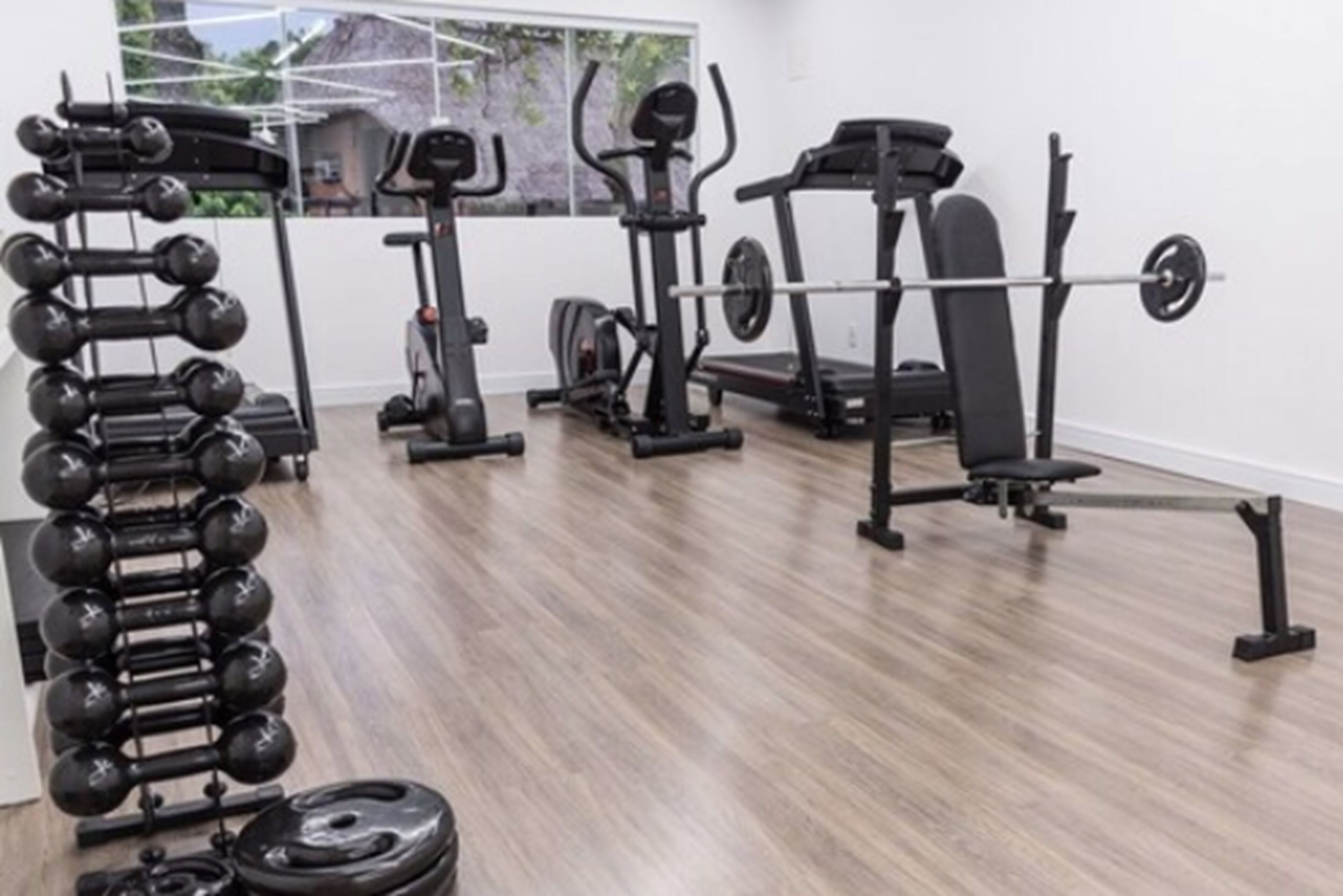 A gym with various exercise equipment including dumbbells, a treadmill, and a barbell.