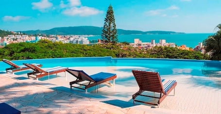 Una piscina al aire libre, sombrillas, sillones reclinables de piscina