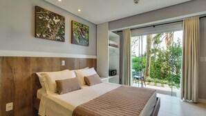Un dormitorio moderno con una cama grande, cabecera de madera y vistas a la vegetación a través de un ventanal corredero.