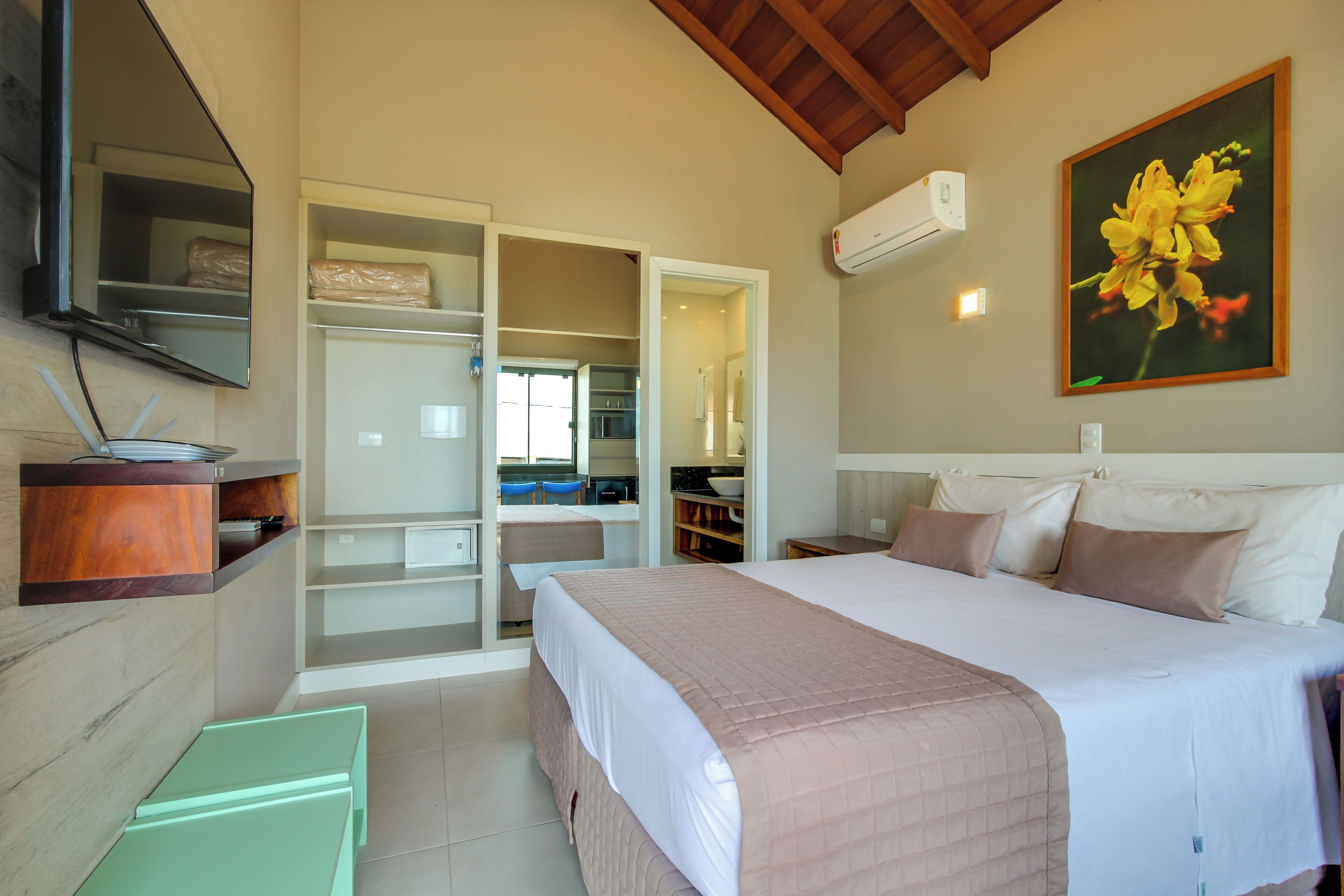 A bedroom with a bed, a wardrobe, a mirror, and a painting.