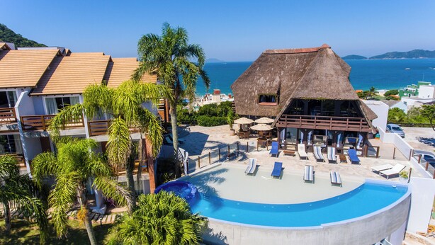 Un resort con piscina, sillones de descanso y una construcción con techo de paja.