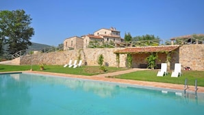 Una piscina con sillas de descanso y un muro de piedra.