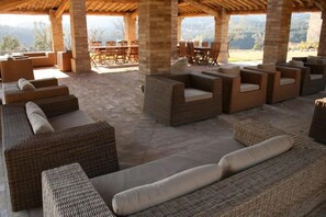 Un patio al aire libre con mobiliario de mimbre y vistas a las montañas.