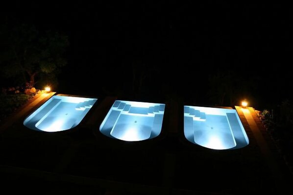 Three illuminated swimming pools at night.
