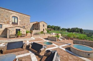 A stone building with outdoor seating and a swimming pool.