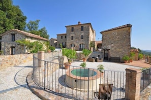 Un patio con edificios de piedra, una piscina circular y mobiliario al aire libre.