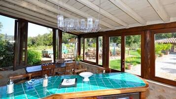 A kitchen with a green-tiled countertop, wooden cabinets, and a view of the outdoor patio area.