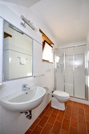 Un baño con lavamanos blanco, inodoro y cabina de ducha de vidrio.