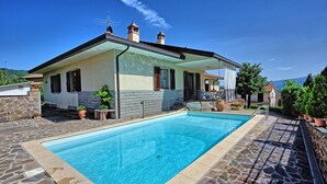 Ein zweistöckiges Haus mit Swimmingpool, Steinmauern und Bergblick.