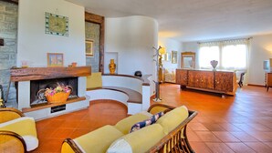 Ein geräumiges Wohnzimmer mit Kamin, einer Couch, einem Holzkabinett und einem Fernseher.