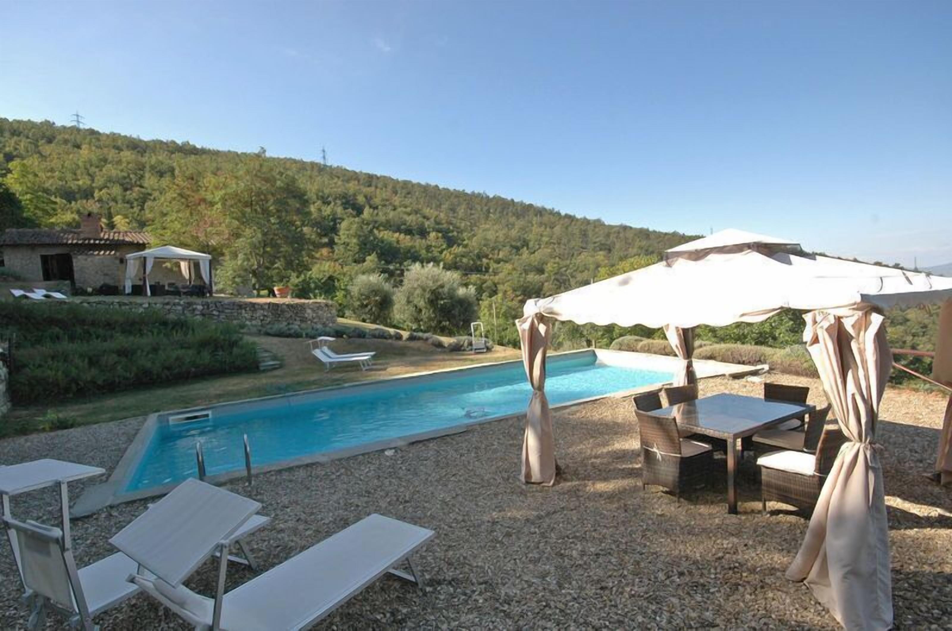 A pool area with lounge chairs, a covered table, and a tent.