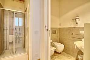 A bathroom with a glass-enclosed shower, a toilet, and a towel rack.