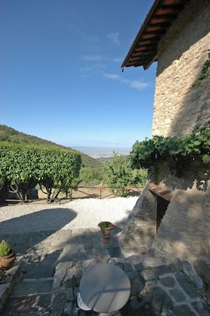 Un bâtiment en pierre offrant une vue sur un vignoble et un paysage lointain.