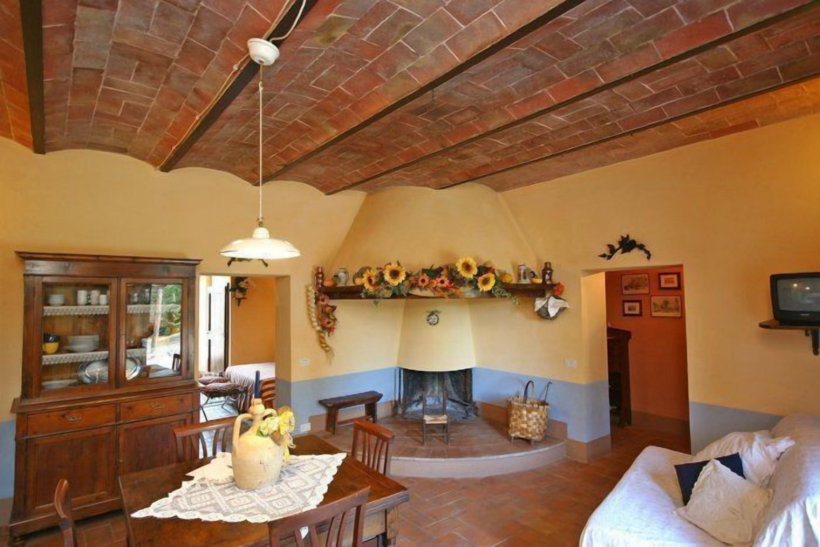 A cozy living room with a fireplace, a dining area with a wooden table and chairs, and a sofa in the corner.