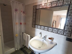 A bathroom with a shower, a sink, and a mirror with a decorative frame. - Villa Le Murate (Passignano sul Trasimeno)