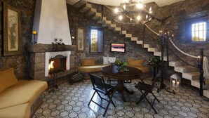 Een gezellige kamer met een stenen openhaard, een ronde eettafel en een comfortabele zithoek.