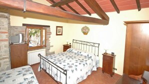 A bedroom with a bed, a wooden cabinet, a small table, and a window. - Annarita (Pratovecchio Stia)