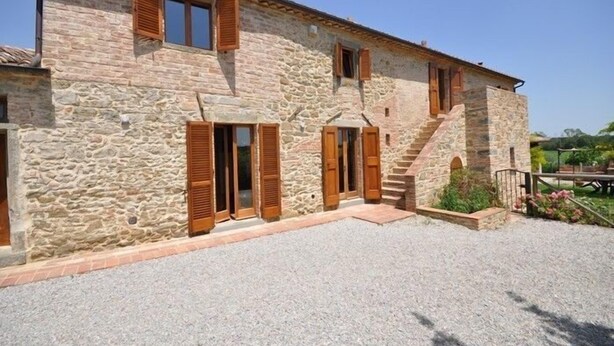 A stone building with wooden shutters, a gravel driveway, and a staircase leading to the entrance. - Poggio Del Sole (Cortona)