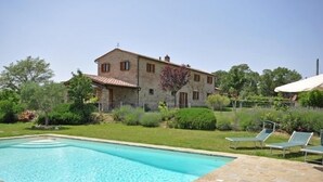 A stone building with a swimming pool and lounge chairs. - Poggio Del Sole (Cortona)