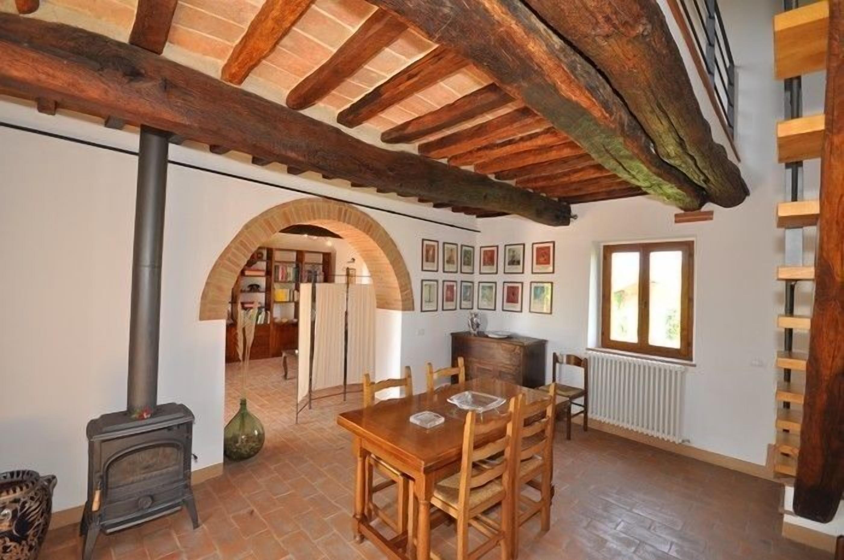 Un comedor con mesa y sillas de madera, chimenea y ventana con vistas.