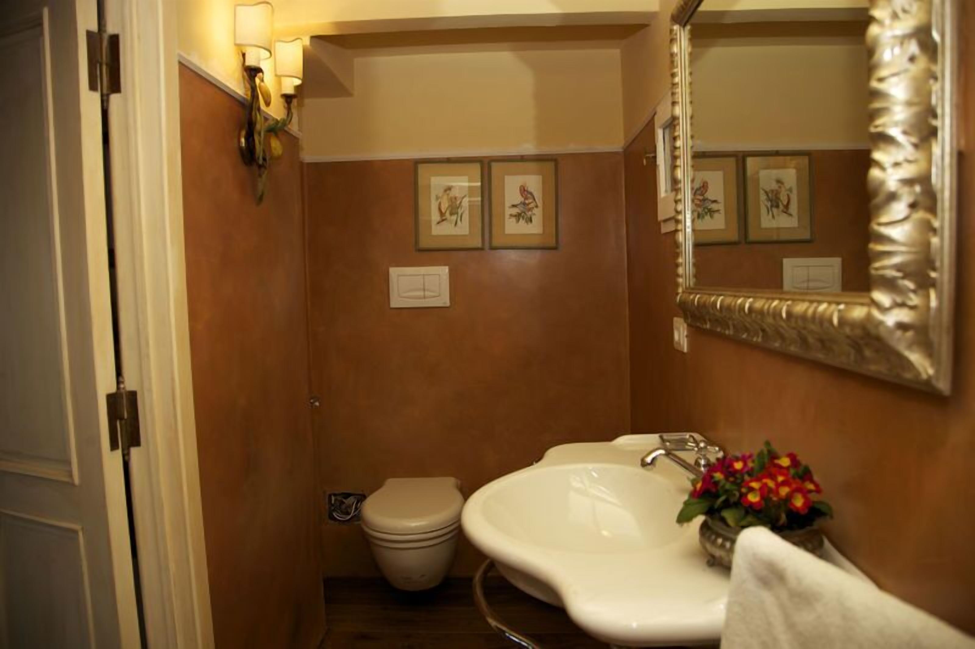 A bathroom with a white sink, a toilet, and framed artwork on the wall.