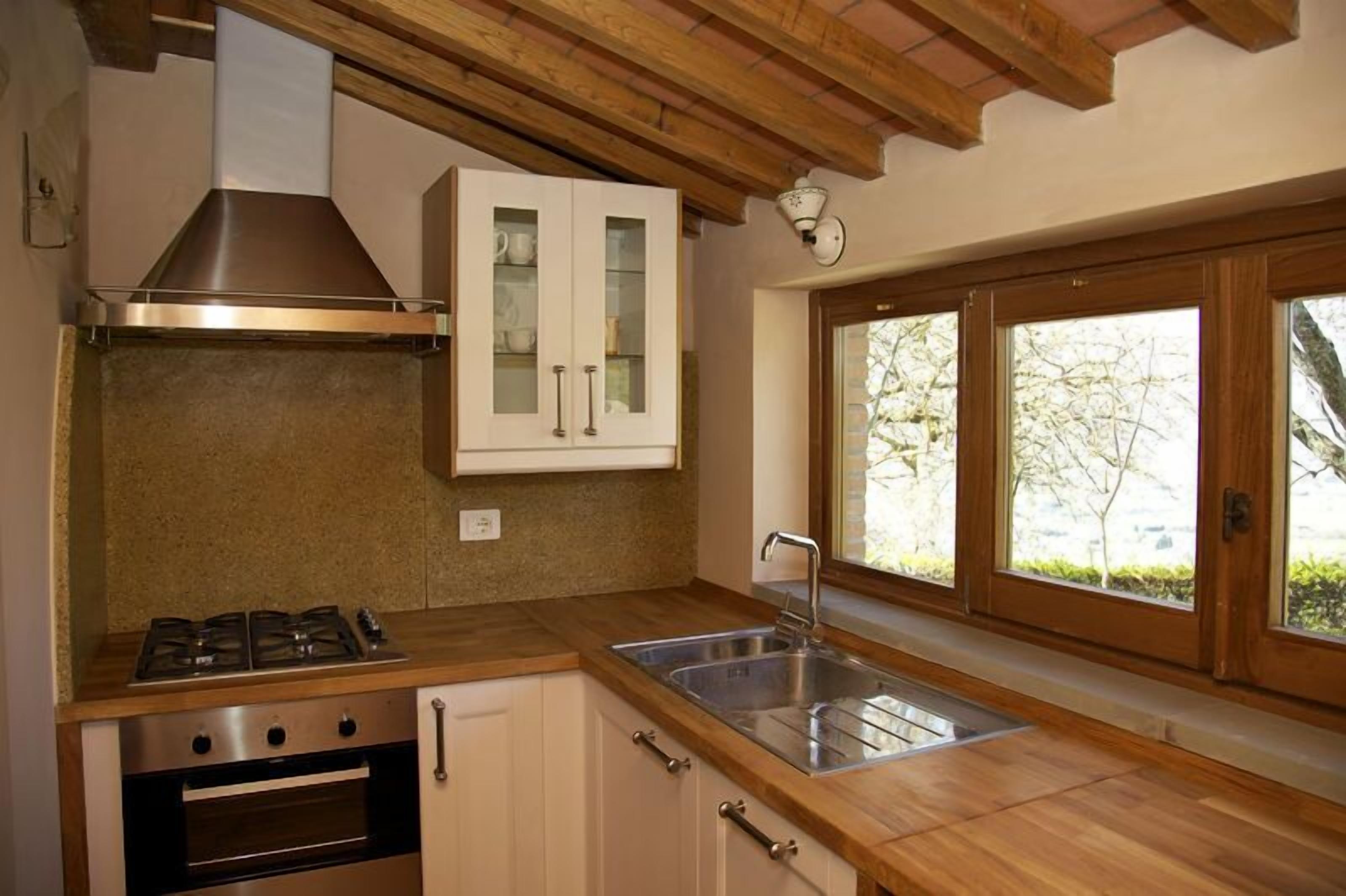 A kitchen with a gas stove, oven, stainless steel sink, and wooden cabinets.