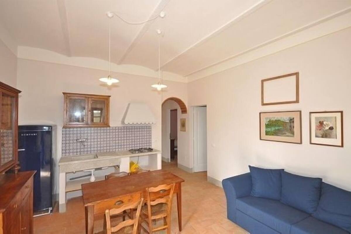 A compact living space with a kitchenette, dining area, and a blue sofa.