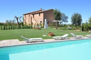 A swimming pool with lounge chairs and a patio area. - Podere Romina (Cortona)