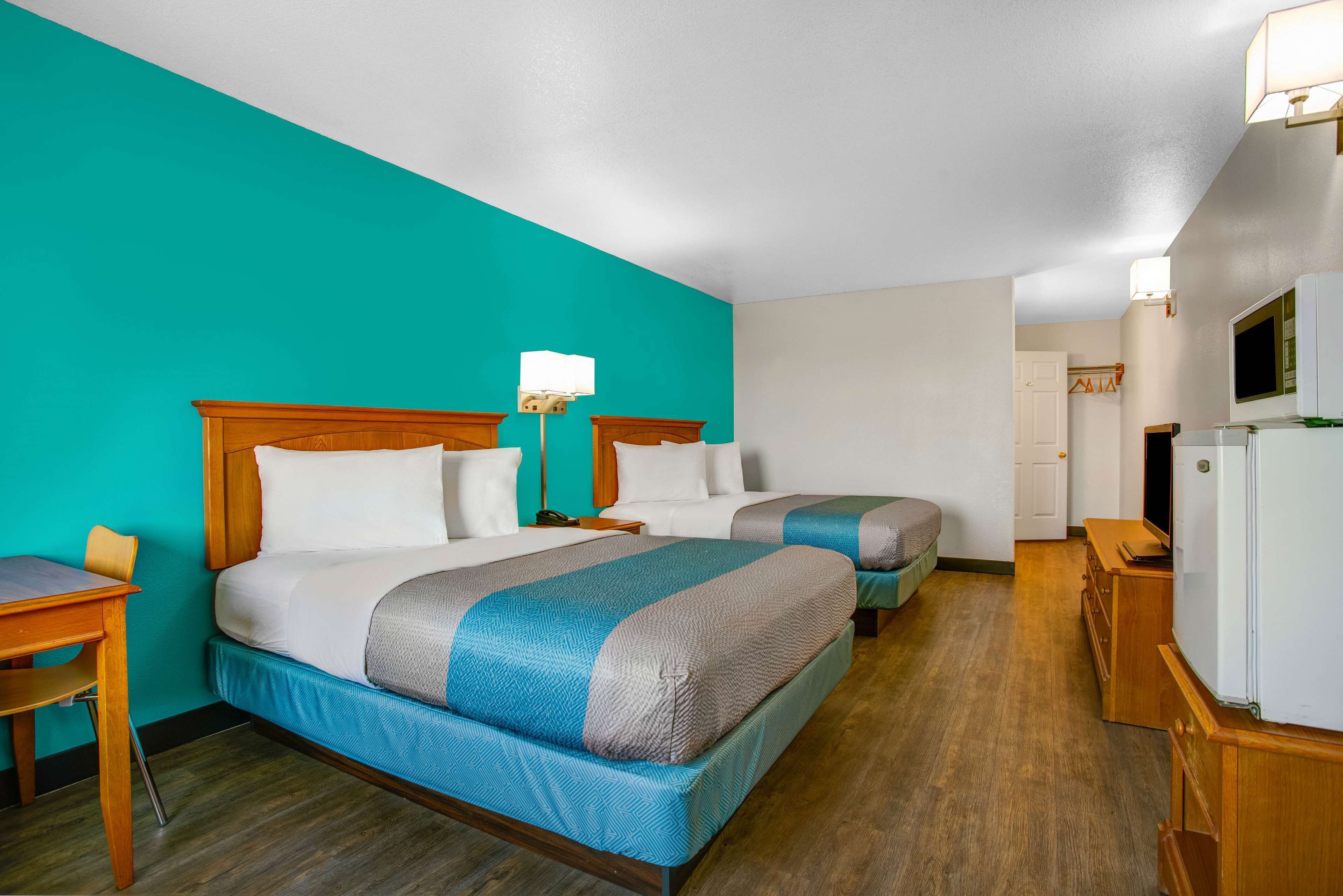 Une chambre d’hôtel avec deux lits, un bureau et une télévision.