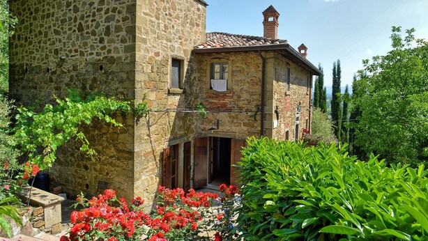 A stone building with a tiled roof, a chimney, and a small window with a towel hanging. - Col Di Forche (Monterchi)